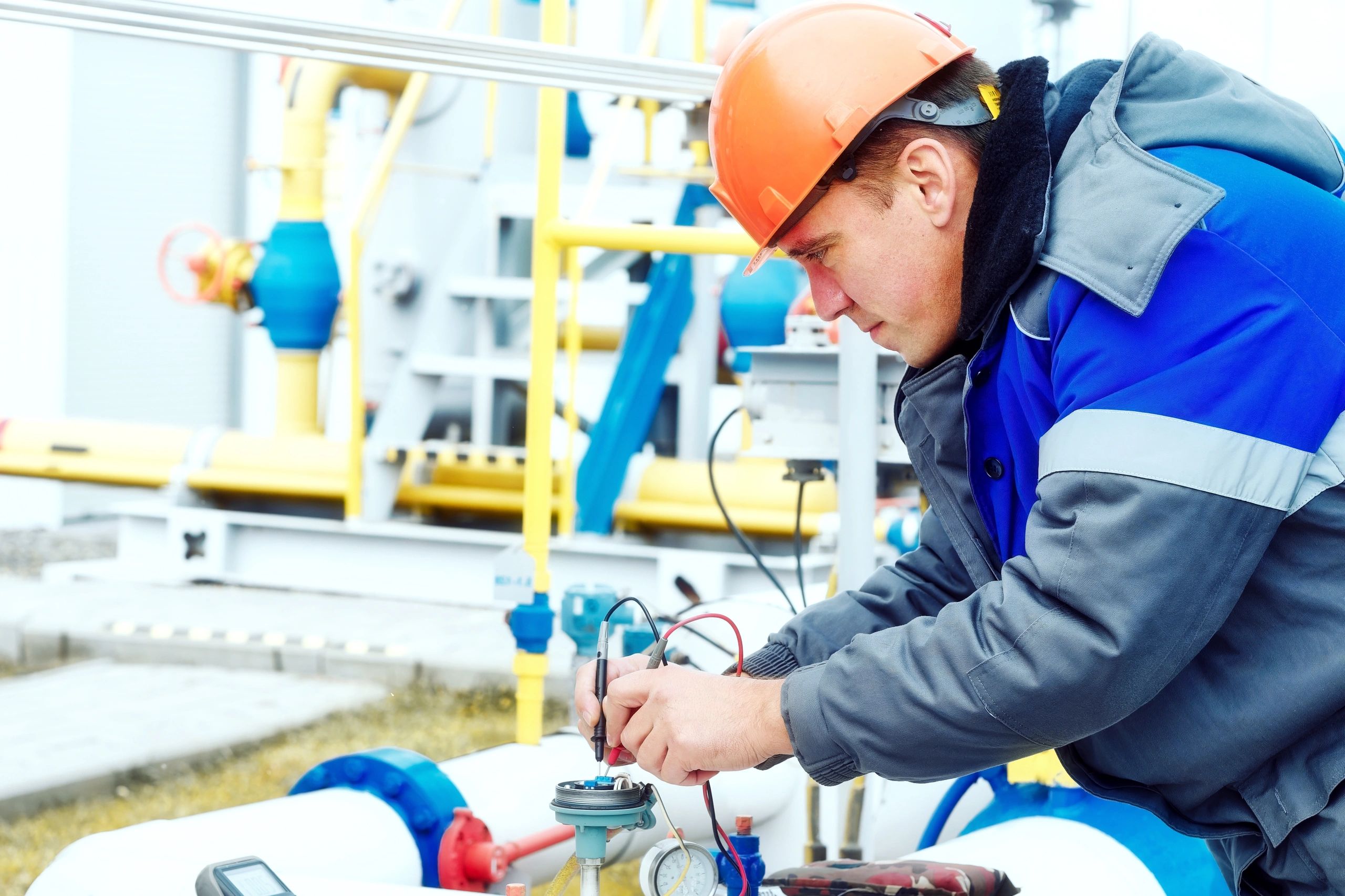 Technician performing inspection on industrial piping with measurement tools