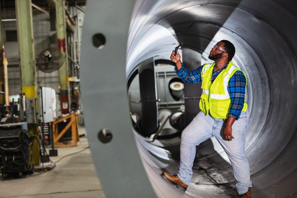 NDT inspector performing visual inspection inside a fabricated steel pipe section