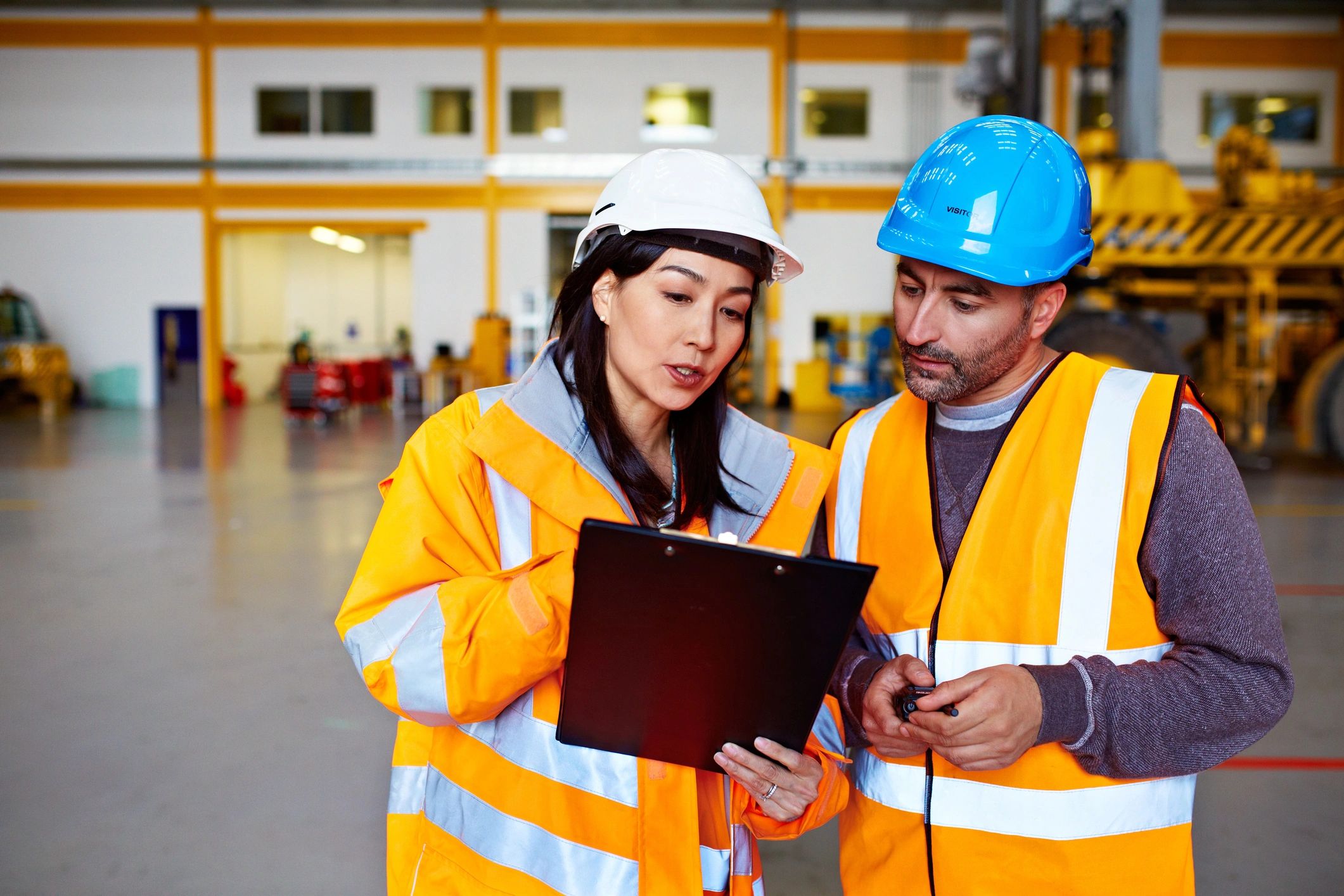 Warehouse workers discussing shipment over a clipboard